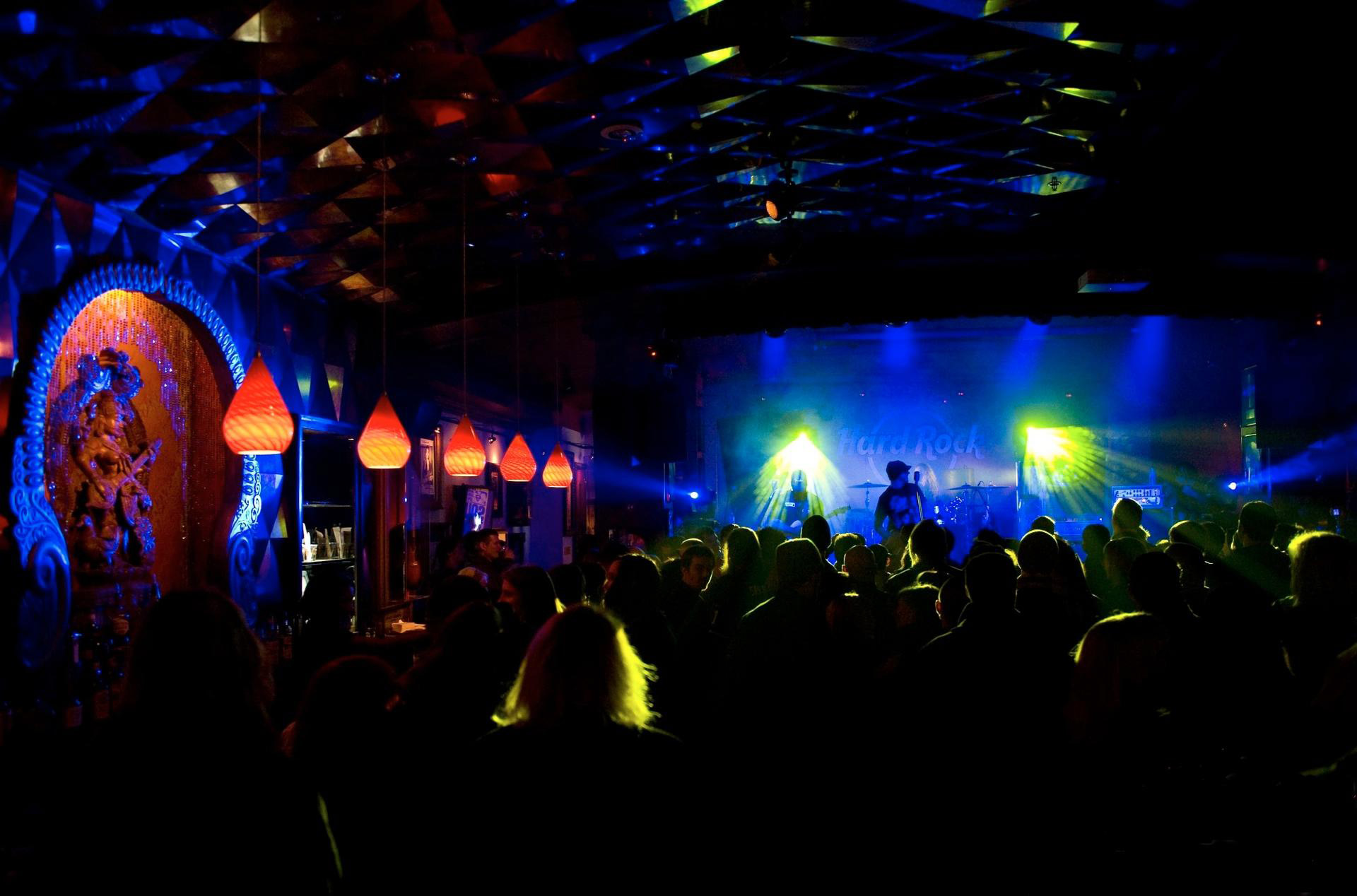 a crowd of people in a dark room with a band playing on stage