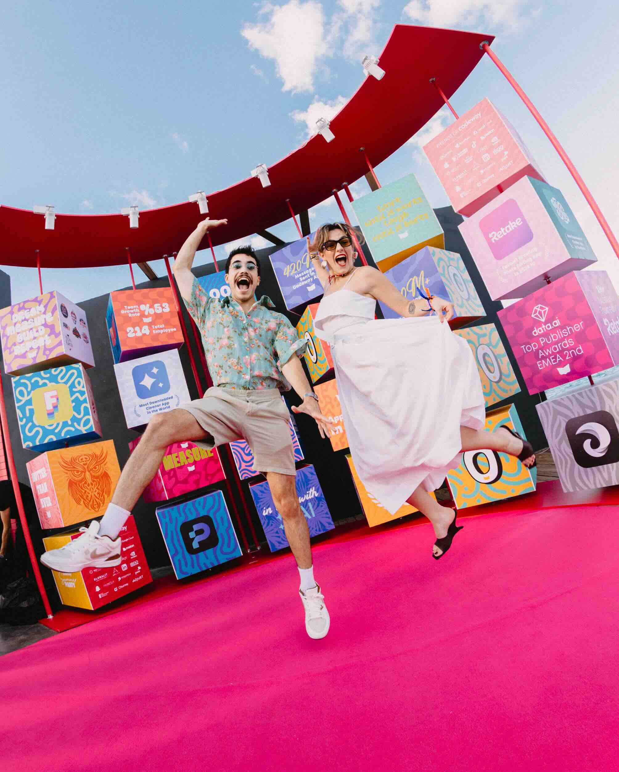 Two people at an outdoor event. They're posing together for a picture jumping in front of the camera.