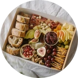 Vesperbrett mit verschiedenen Käsesorten, Trauben, Feigen, Nüssen, Crackern und Brotscheiben.