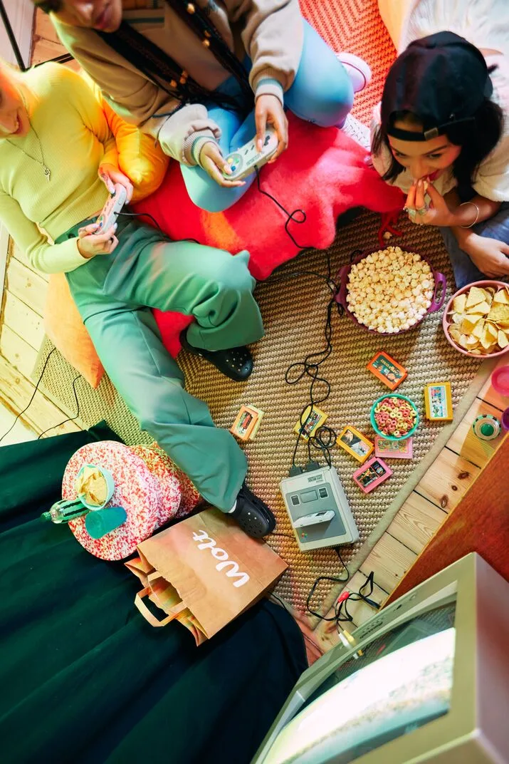 People are sitting in front of the TV to play video games and enjoying the food delivered by Wolt. 