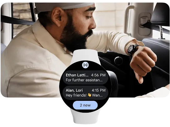 A man is in the backseat of a car with his left arm raised closer to his face as he is looking at a notification on his smartwatch. He is leaning forward and holding the back of the driver’s seat, appearing to be on-the-go and in a hurry.