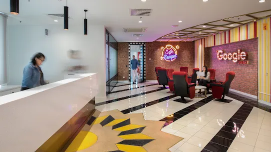 レンガの壁、白黒のタイル張りの床、赤色の座席が備えられたワークスペース。